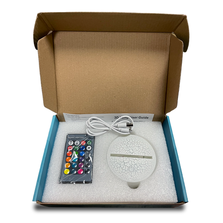 Open box of 3D lamp showing the control, base, and USB cable for setup.