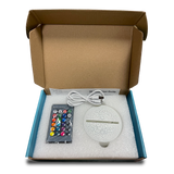 Open box of 3D light showing the control, base, and USB cable for setup.